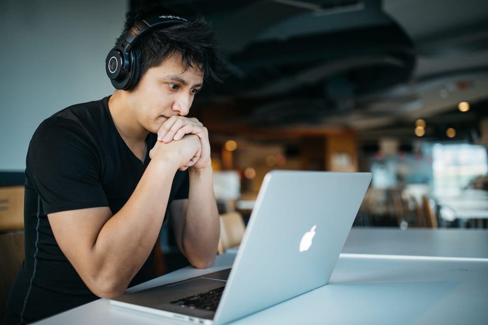 Man working on his Macbook with headphones on